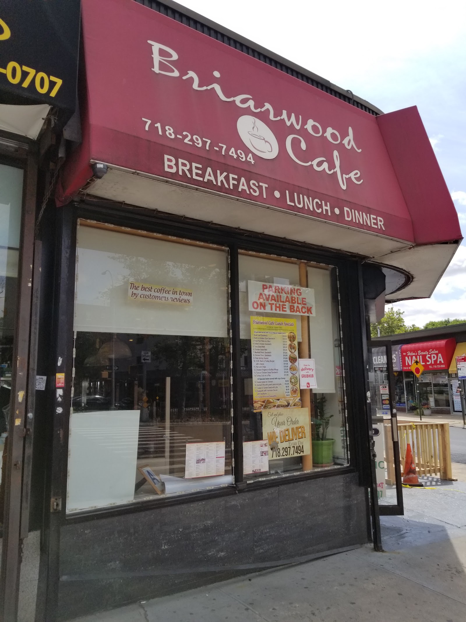 The Briarwood Cafe storefront on Queens Boulevard: a deep burgundy awning carrying the name in cream script either side of a line-drawn coffee cup, the phone number 718-297-7494, and the words Breakfast, Lunch, Dinner along the bottom edge